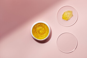 Cosmetic product with particles in container and petri dish on pink background. Sample natural skin...