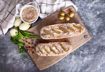 Sandwiches with meat pate and pickled cucumber on a wooden cutting board, top view. Rustic...
