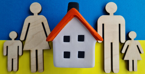 Wooden figurines of family with a house on background of Ukrainian flag
