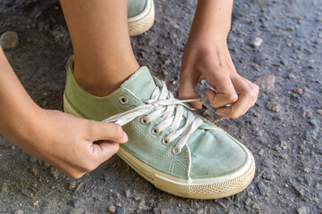 child ties shoelaces on sneakers