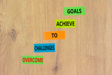 Overcome challenges to achieve goals symbol. Concept words Overcome challenges to achieve goals on color papers on a beautiful wooden background. Business goals concept. Copy space.