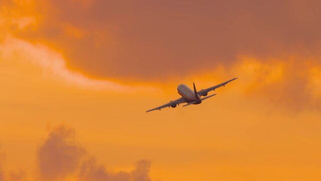 Passenger airplane flying at sunset. Long shot of an airliner taking off gaining altitude. Cinematic footage of a jet plane in the sunset fire sky