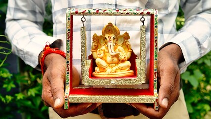 Hands holding Lord Ganesha idol in palm background for Visarjan or Immersion. Lord Ganapati idol...