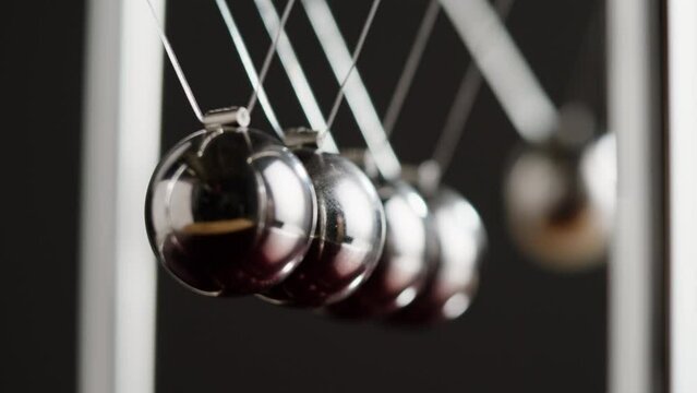 Newton balls close-up, five metallic pendulums on black background, cradle. Physics and science concept.