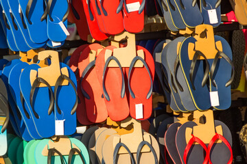 Showcase with blue, red and other colors of beach flip-flops in a shoe store.