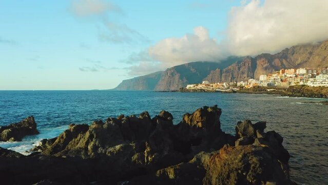 Tourist girl relax. Tenerife, Canary Island, Charco el Diablo or natural pool of Devil. Lava flows, volcanic bizzare stones, rocky beach on Atlantic Ocean. Scenic spot. Amazing nature formations.