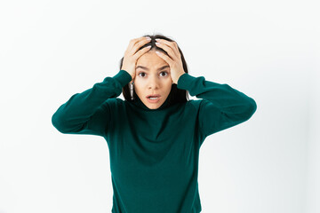 Portrait of young woman in panic holding her head looks scared
