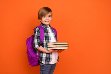 Profile side photo of young boy hold book information materials isolated over orange color background