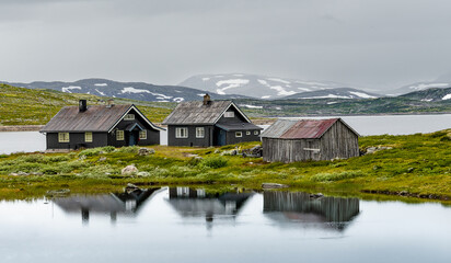 Drei H&auml;user am Bergsee in Norwegen mit Spiegelung im See