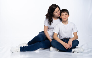 Fototapeta na wymiar woman with a boy. Mom with son on a white background. family portrait in white t-shirts and blue jeans