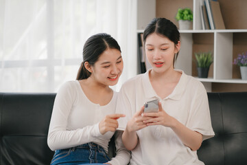 Asian woman happy holding laptop phone sitting sofa smiling good mood indoors indoors