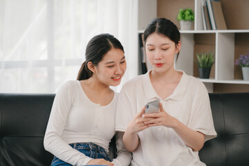 Asian woman happy holding laptop phone sitting sofa smiling good mood indoors indoors