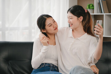 Asian woman happy holding laptop phone sitting sofa smiling good mood indoors indoors