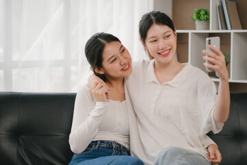 Asian woman happy holding laptop phone sitting sofa smiling good mood indoors indoors