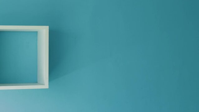Slow pan shot of white cube shelves on a beautiful blue wall