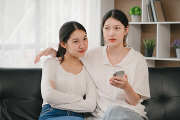 Asian woman happy holding laptop phone sitting sofa smiling good mood indoors indoors