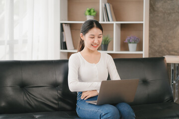 Asian woman happy holding laptop phone sitting sofa smiling good mood indoors indoors