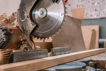 Sawing machine for wood in the workshop for the production of furniture. Woodworking circular saw and wooden bar for cutting.