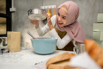 Young beautiful muslim woman is baking in her kitchen , bakery and coffee shop business
