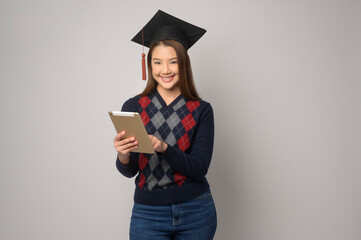 Young smiling woman holding graduation hat, education and university concept.
