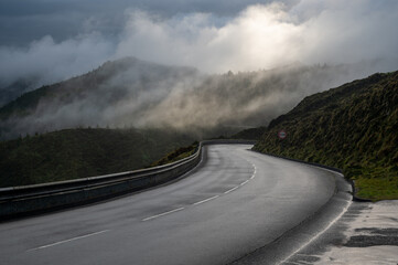 Wet winding mountain road covered in clouds