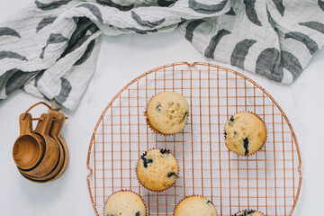 Homemade blueberry muffins baked to perfection on cooling rack in modern white marble kitchen.