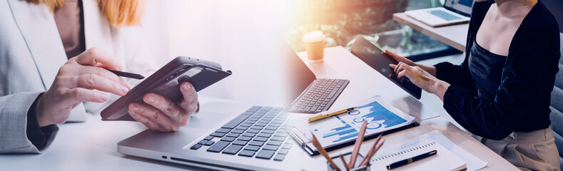 Business team finance or bookkeeper working with a calculator to calculate business data summary report, accountancy document and laptop computer at the office, business meeting concept