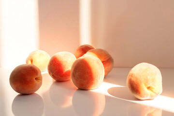 Ripe juicy peaches lying on the table with reflection on surface under the rays of the sun on bright background. Selective focus. Blurred background.