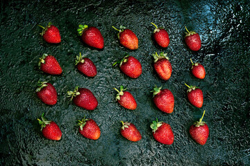 Set of ripe red strawberries on dark background. Strawberry pattern. Dark low key photo. Flat lay composition.