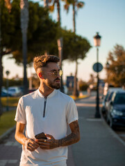 Hombre joven con tatuajes usando su teléfono móvil