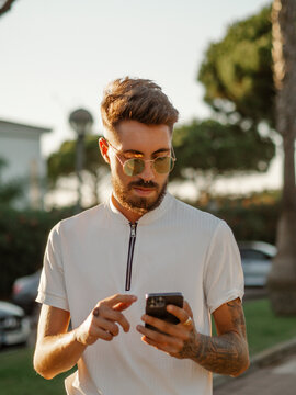 Hombre joven con tatuajes usando su tel&eacute;fono m&oacute;vil