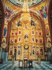 Fototapeta na wymiar The altar and beautiful painted interior of the Curchi Monastery. Suspending golden chandelier with glowing lights. Different icons of saints as traditional for Christian Orthodox churches in Moldova