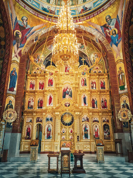 The altar and beautiful painted interior of the Curchi Monastery. Suspending golden chandelier with glowing lights. Different icons of saints as traditional for Christian Orthodox churches in Moldova