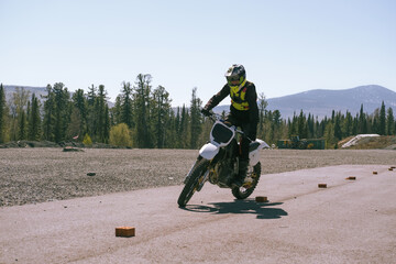 Beginner motorcyclist wearing a gear, helmet and protection, training on the ground on dirt...