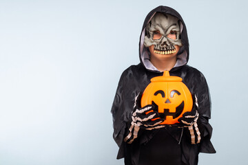 Happy Halloween! Cute little boy in a costume with a pumpkin basket jack-o-lantern