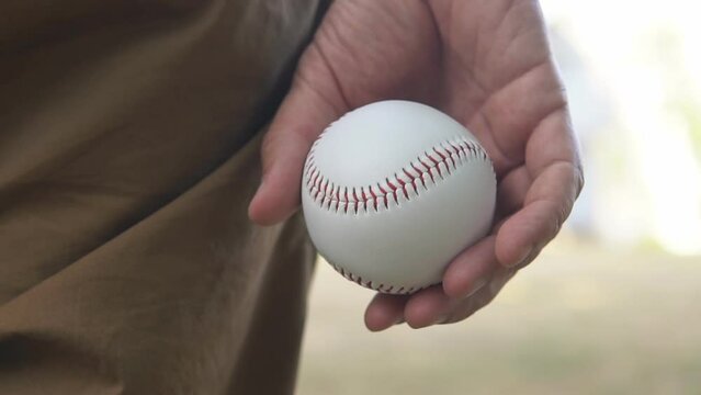 Baseball pitcher holding a baseball ball in his hands, slow motion