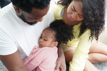 Shot of happy interracial family of mother father and their daughter inside modern apartment.