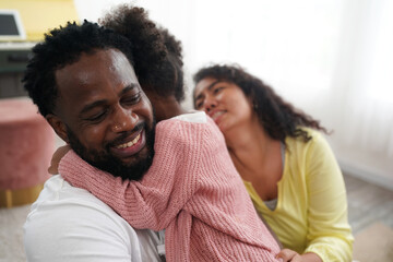 Shot of happy interracial family of mother father and their daughter inside modern apartment.