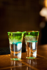 Two white-green alcoholic drinks shots on the bar counter