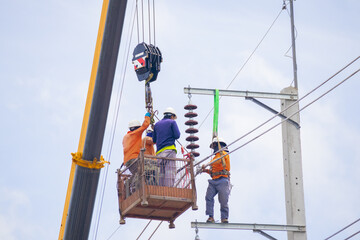An electrician climbs a cable car and a light pole with safety devices to install a new electrical...