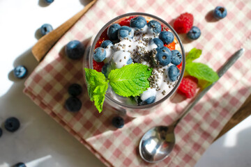 Yogurt, chia seeds, raspberries
, strawberries, blueberries, mint on a light background