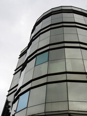 The glazed facade of a high-rise building against a gray, harsh winter sky. Styles of modern architecture, glass and metal.