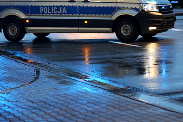 Policjanci ruchu drogowego podczas opadów deszczu kierują ruchem w mieście wieczorem. 