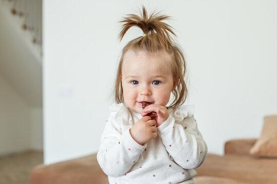 Little Baby Toddler Eats Sweet Healthy Fruit Paste Rolls. Fruit-flavored Snack Rolled Into Tube.