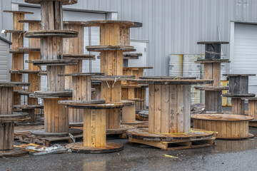 Stacks of large empty ommercial wooden electrical cable spools in an alley outside a business, daytime, nobody