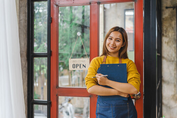 Young Asian freelancer coffee shop owner standing with open sign, standing front of the door.