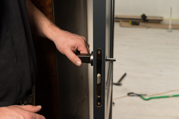 A carpenter installs a metal doorknob for an interior door,