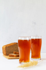 glass of beer on wooden table.two high Glasses of fresh kvass with bread on white background with...