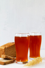 two high Glasses of fresh kvass with bread on white background with copy space. vertical