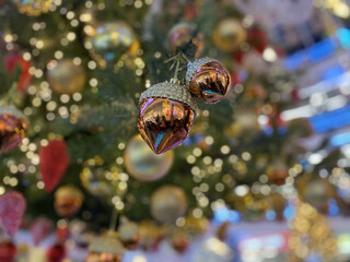 Green branches of a fluffy Christmas festive New Year tree with toys in balls and bright glowing light bulbs and garlands, background.
